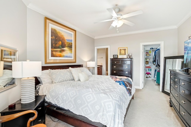 bedroom featuring a walk in closet, ornamental molding, a closet, ceiling fan, and light carpet