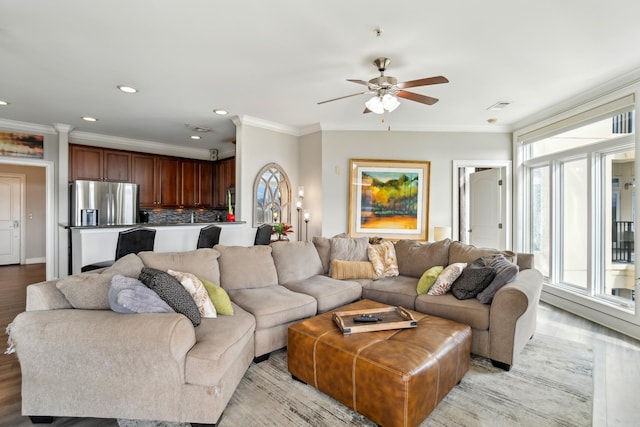 living room with ornamental molding, light hardwood / wood-style flooring, and ceiling fan