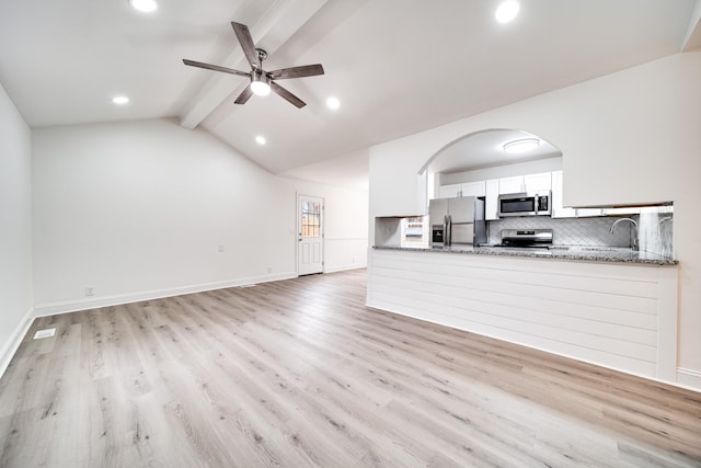 unfurnished living room with sink, ceiling fan, light wood-type flooring, and vaulted ceiling with beams