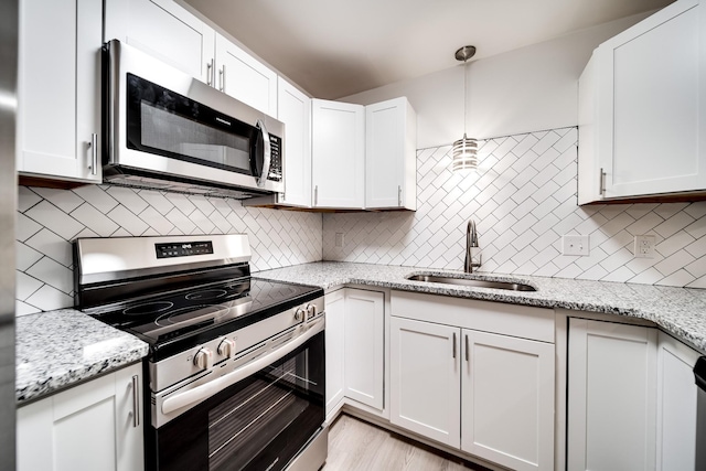 kitchen featuring white cabinets, decorative light fixtures, stainless steel appliances, and sink