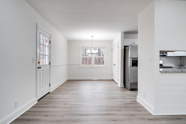 unfurnished dining area featuring light wood-type flooring and an inviting chandelier