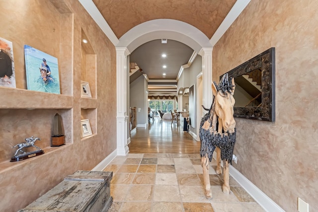 corridor with lofted ceiling, ornate columns, and ornamental molding