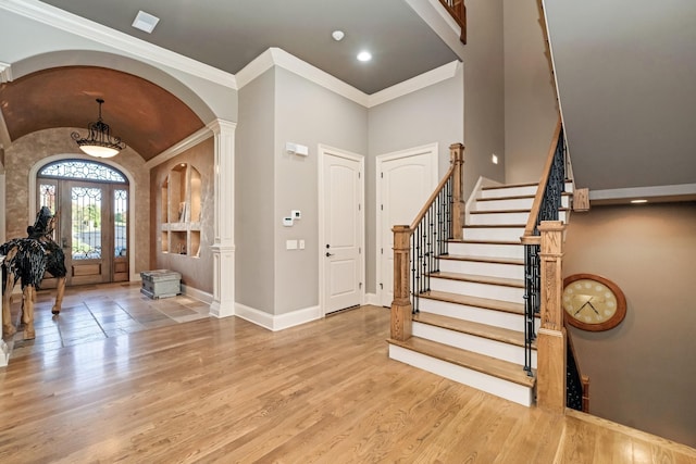 foyer entrance with ornate columns, lofted ceiling, crown molding, and light hardwood / wood-style floors