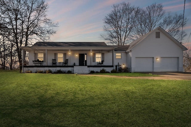 ranch-style home featuring covered porch, a garage, and a lawn