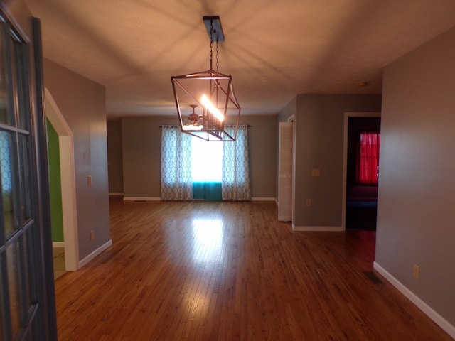 unfurnished room with dark wood-type flooring and an inviting chandelier