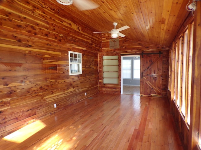 spare room featuring wood ceiling, wood walls, vaulted ceiling, and a barn door