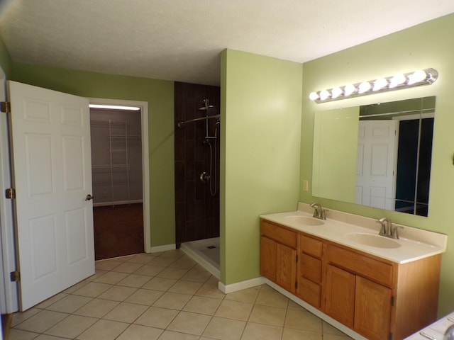 bathroom featuring a textured ceiling, a tile shower, vanity, and tile patterned flooring