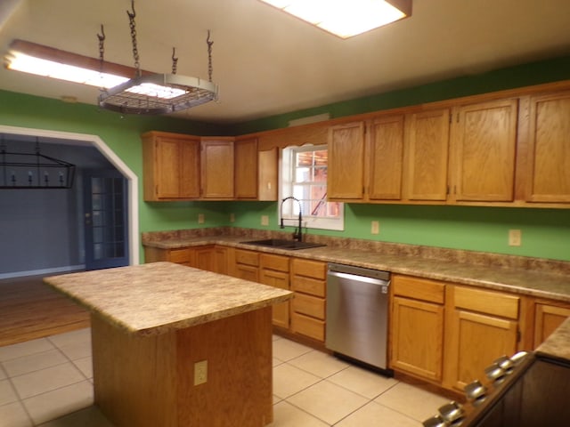 kitchen with sink, stainless steel dishwasher, a center island, and light tile patterned floors