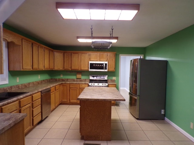 kitchen featuring light tile patterned floors, stainless steel appliances, a kitchen island, and sink