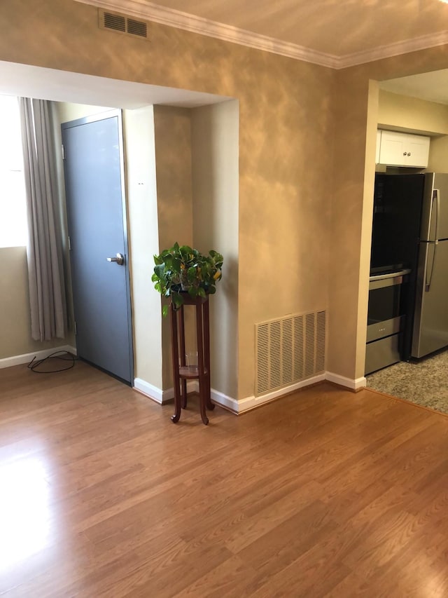 spare room with light hardwood / wood-style floors and crown molding