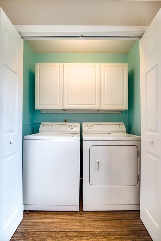 laundry room featuring washer and dryer, cabinets, a textured ceiling, and hardwood / wood-style floors