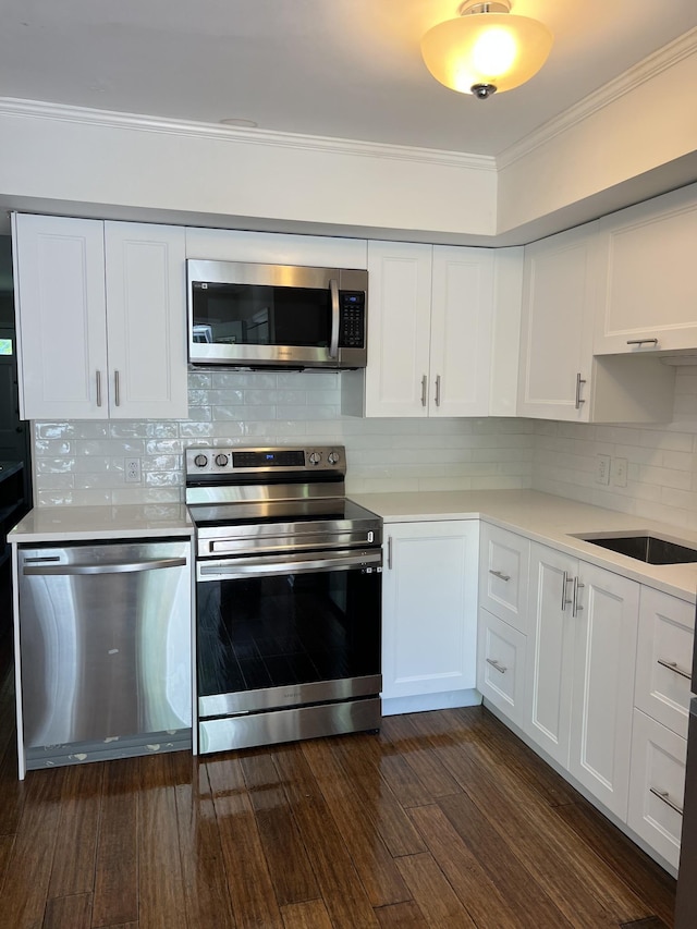 kitchen with white cabinetry, stainless steel appliances, crown molding, dark hardwood / wood-style floors, and decorative backsplash