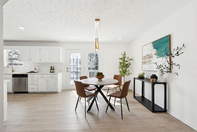 dining area with light wood-style floors, a textured ceiling, and recessed lighting