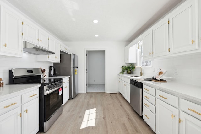 kitchen featuring tasteful backsplash, stainless steel appliances, under cabinet range hood, white cabinetry, and a sink