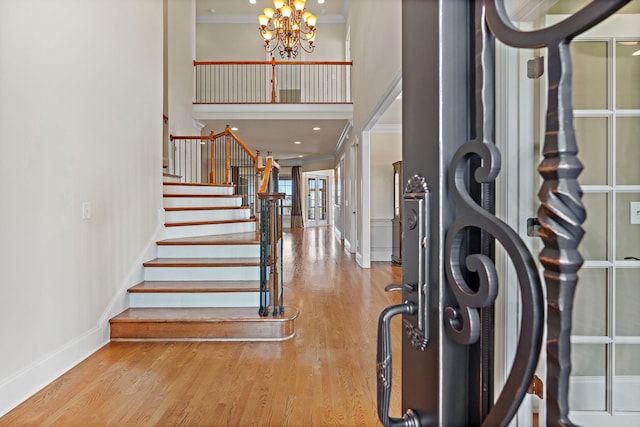 foyer featuring hardwood / wood-style flooring, crown molding, a chandelier, and a towering ceiling