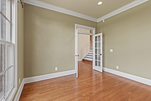 unfurnished room featuring light hardwood / wood-style floors, crown molding, and french doors