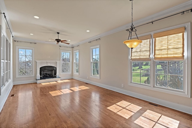 unfurnished living room with a high end fireplace, crown molding, ceiling fan, and light hardwood / wood-style flooring