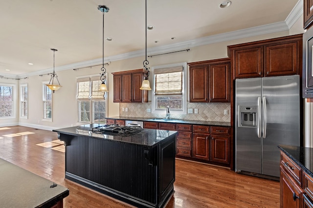 kitchen featuring ornamental molding, a kitchen island, stainless steel appliances, and hanging light fixtures