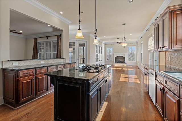 kitchen featuring appliances with stainless steel finishes, hanging light fixtures, backsplash, hardwood / wood-style floors, and a kitchen island