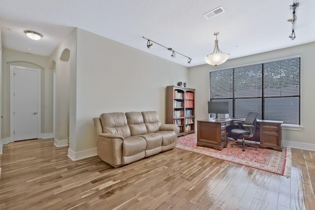 home office with light hardwood / wood-style flooring and a textured ceiling