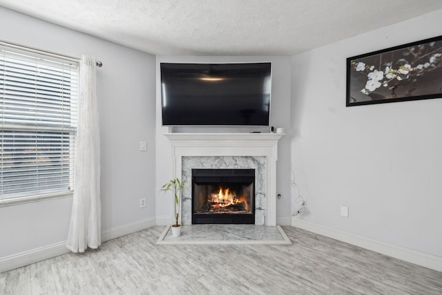 unfurnished living room featuring a textured ceiling, hardwood / wood-style floors, plenty of natural light, and a premium fireplace