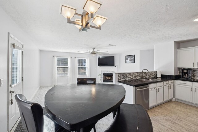 dining room with sink, light hardwood / wood-style floors, a high end fireplace, and a healthy amount of sunlight