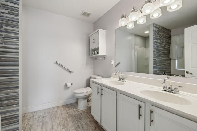 bathroom with hardwood / wood-style flooring, vanity, toilet, and walk in shower