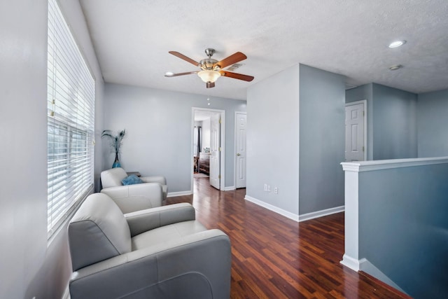 living area featuring a textured ceiling, dark wood-type flooring, and ceiling fan