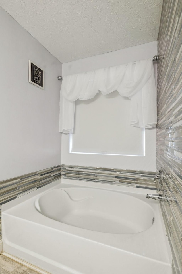 bathroom featuring a textured ceiling and a bathtub