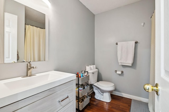 bathroom with toilet, vanity, and hardwood / wood-style floors