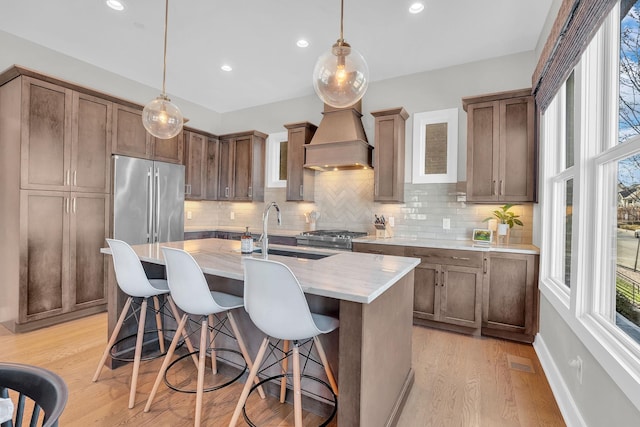 kitchen featuring sink, a center island with sink, hanging light fixtures, and a wealth of natural light