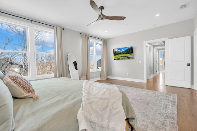 bedroom featuring multiple windows, wood-type flooring, and ceiling fan