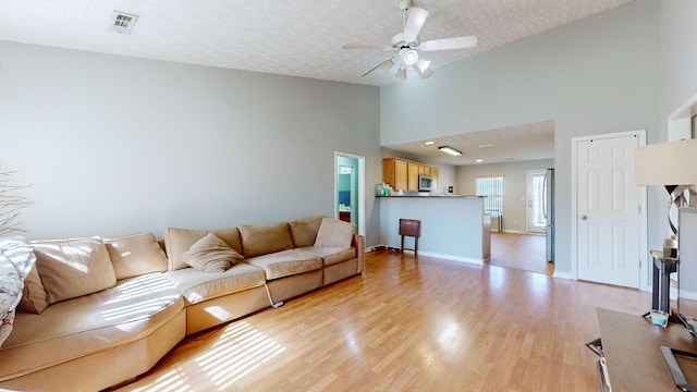 living room with ceiling fan, light hardwood / wood-style flooring, and a textured ceiling