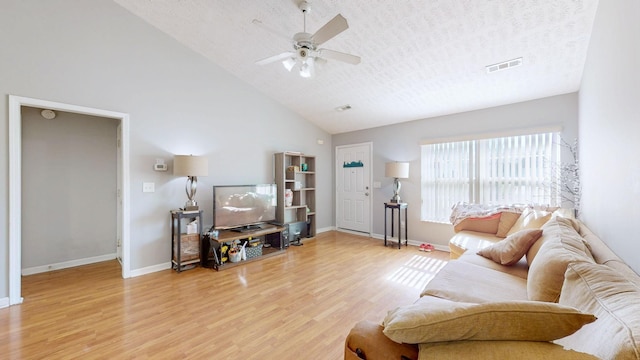 living room with hardwood / wood-style flooring, ceiling fan, high vaulted ceiling, and a textured ceiling