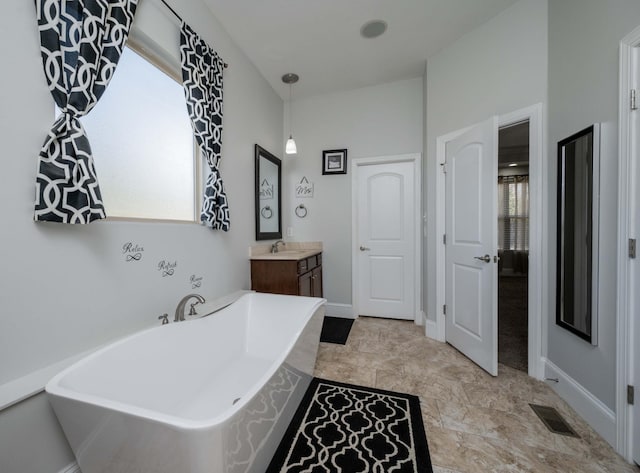 bathroom featuring a freestanding tub, baseboards, visible vents, and vanity