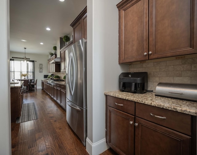 kitchen with light stone counters, stainless steel appliances, baseboards, backsplash, and dark wood-style floors