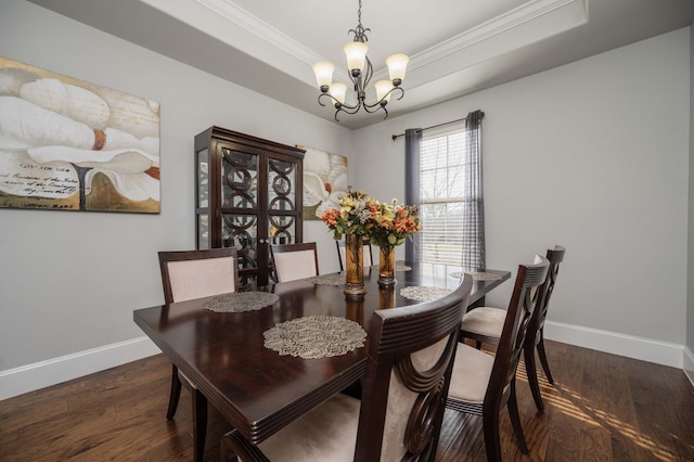 dining area with a chandelier, a tray ceiling, baseboards, and wood finished floors