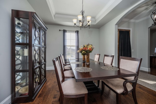 dining room featuring baseboards, arched walkways, a raised ceiling, dark wood-style floors, and ornamental molding