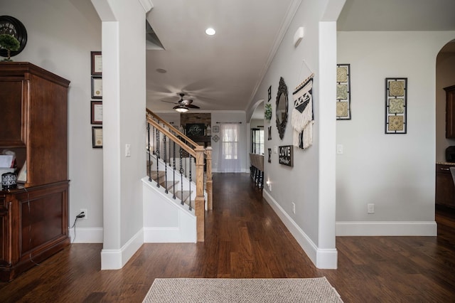 entryway featuring baseboards, arched walkways, wood finished floors, stairs, and crown molding