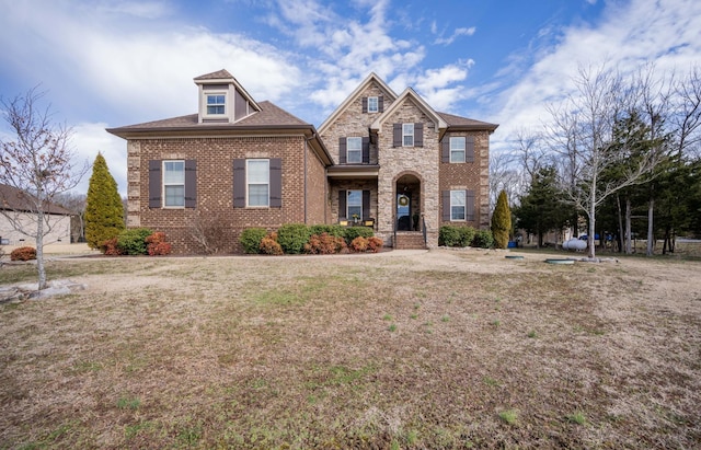 view of front facade with stone siding, brick siding, and a front lawn