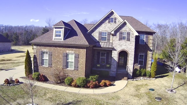 view of front of house featuring stone siding, brick siding, and roof with shingles