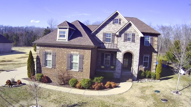 view of front of house with stone siding, brick siding, and roof with shingles