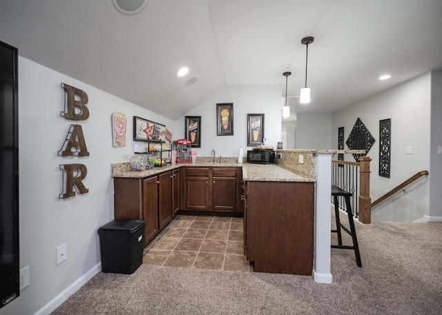 kitchen with light colored carpet, light stone counters, a breakfast bar, a peninsula, and a sink