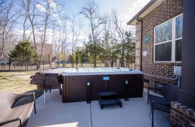 view of patio / terrace with a hot tub and fence