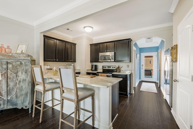 kitchen featuring light stone countertops, dark wood-type flooring, a breakfast bar area, and stainless steel appliances