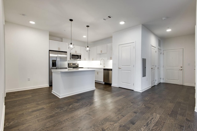 kitchen featuring a center island, white cabinetry, dark hardwood / wood-style floors, stainless steel appliances, and hanging light fixtures