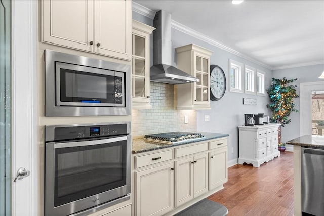 7144 Triple Crown Ln, Fairview, TN 37062 - kitchen with cream cabinetry, stainless steel appliances, glass insert cabinets, wall chimney range hood, and dark stone counters