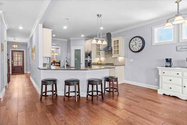 7144 Triple Crown Ln, Fairview, TN 37062 - kitchen featuring appliances with stainless steel finishes, glass insert cabinets, dark stone countertops, wall chimney range hood, and pendant lighting