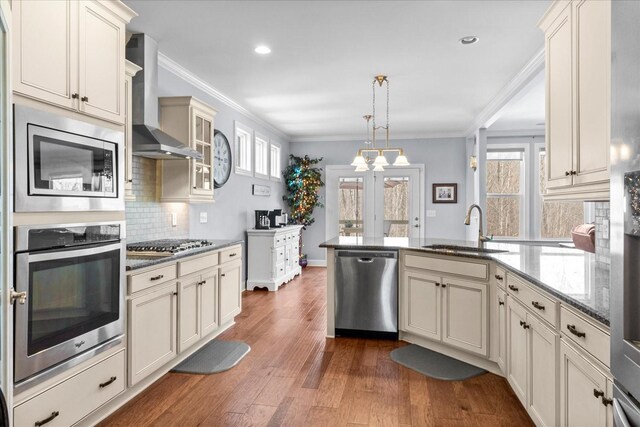 7144 Triple Crown Ln, Fairview, TN 37062 - kitchen featuring cream cabinets, stainless steel appliances, a sink, wall chimney exhaust hood, and pendant lighting