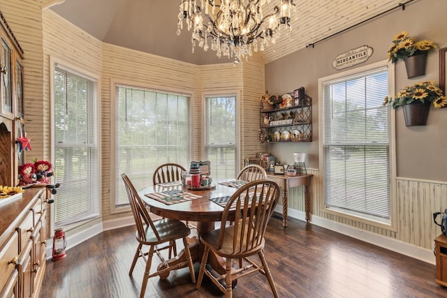 dining space featuring dark wood-type flooring, wooden walls, and an inviting chandelier